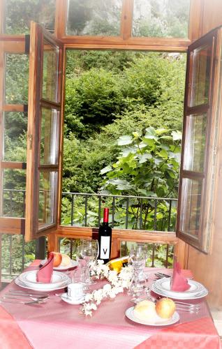 a table with a pink table cloth and a bottle of wine at Hotel Puente Vidosa in Amieva