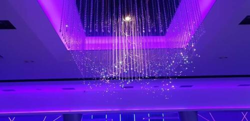 un soffitto viola con lampadario pendente e luci viola di VILIN a Niš
