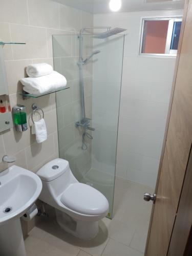 a bathroom with a toilet and a glass shower at Torre Real IV L3 Santiago DR con cocinero para desayuno in Santiago de los Caballeros