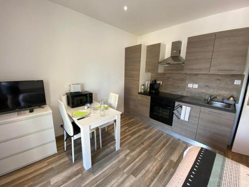 a small kitchen with a white table and a microwave at Legend- Parking privé Gratuit- Terrasse privée- Wifi - Convert - Alimentec in Bourg-en-Bresse
