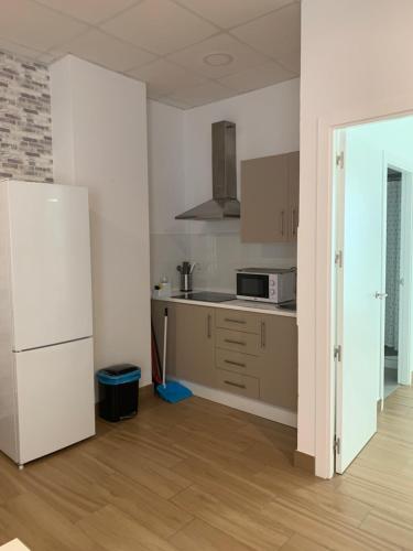 a kitchen with a white refrigerator in a room at Apartamentos Costa de la Luz Béjar 28-30 in Huelva