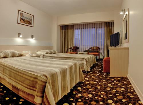 a hotel room with two beds and a television at Yumukoglu Hotel in İzmir