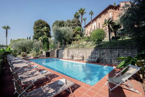 una piscina con sedie a sdraio e un edificio di Hotel Bellevue a Gardone Riviera