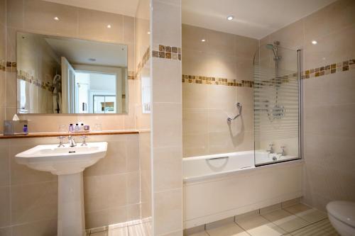 a bathroom with a sink and a shower and a toilet at Macdonald Frimley Hall Hotel & Spa in Camberley
