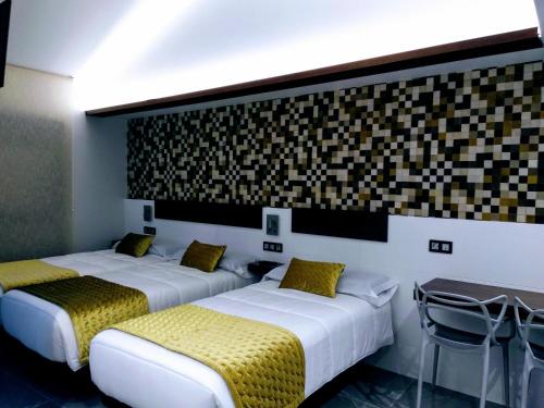 two beds in a hotel room with yellow pillows at Hostal Canton Plaza in Hospital de Órbigo