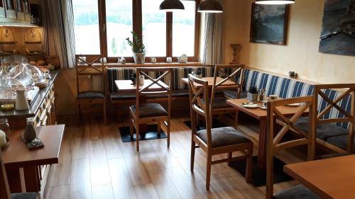 ein Restaurant mit Holztischen, Stühlen und Fenstern in der Unterkunft Haus Rohr in Weissensee