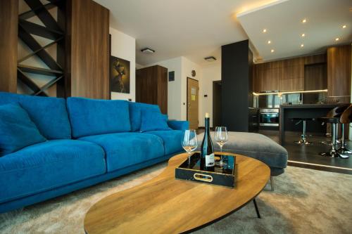 een woonkamer met een blauwe bank en een houten tafel bij Gente Apartments in Cluj-Napoca