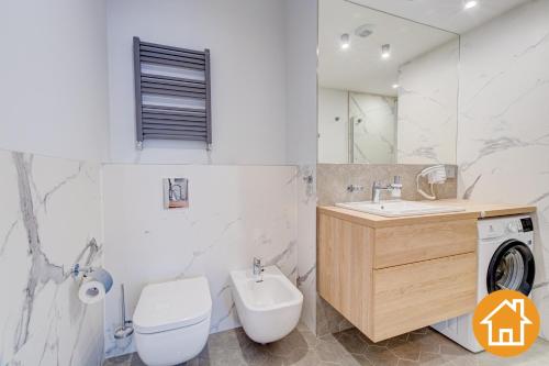 a bathroom with a toilet and a sink and a washing machine at Apartamenty ApartPark - visitopl in Świnoujście