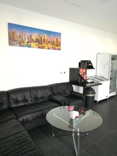 a living room with a black leather couch and a glass table at Jura Hotel in Nürnberg