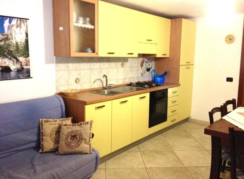 a kitchen with yellow cabinets and a blue couch at Villetta Tancau in Santa Maria Navarrese