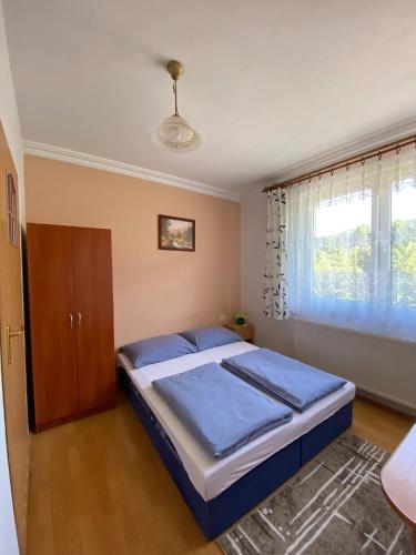 a bedroom with a bed with blue sheets and a window at Noclegi "Na Szczyrboku" Dom I in Korbielów