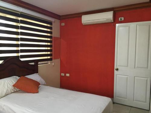 a bedroom with two beds and a red wall at Hotel Fika Guayaquil in Guayaquil