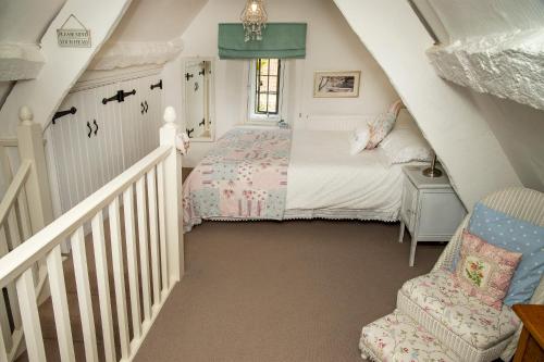 a small bedroom with a bed and a chair at The Burrow in Chideock