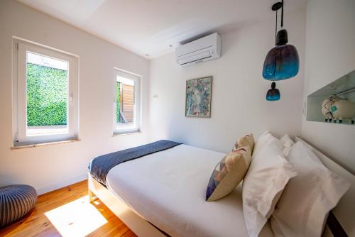 a white bedroom with a bed and two windows at Chiado Oasis with Private Garden by NestAtLisbon in Lisbon