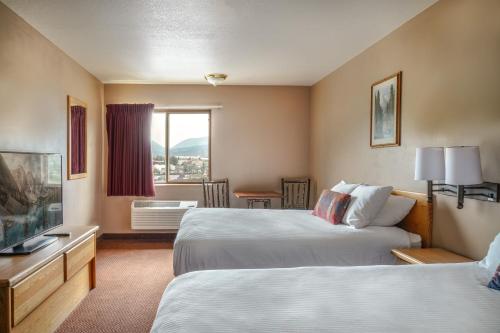 a hotel room with two beds and a flat screen tv at Whitewater Inn in Big Sky