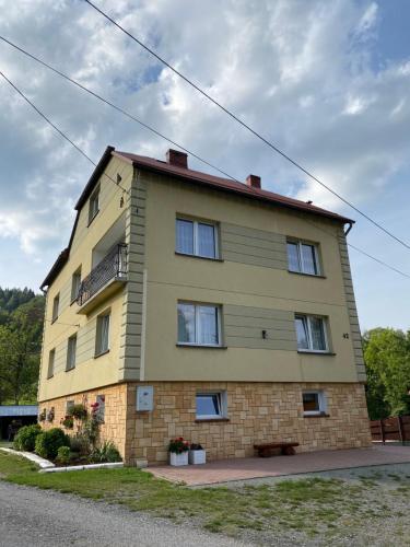 a large yellow building with a balcony at Noclegi "Na Szczyrboku" Dom I in Korbielów