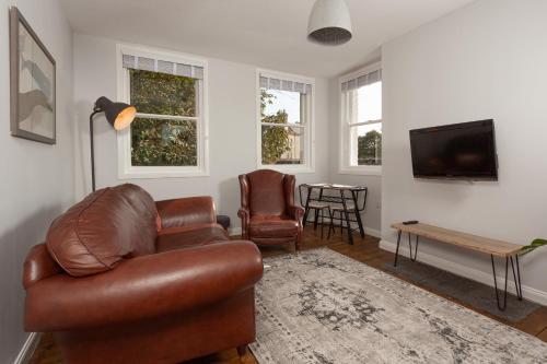 a living room with a leather couch and a table at The Drawing Office in Berwick-Upon-Tweed