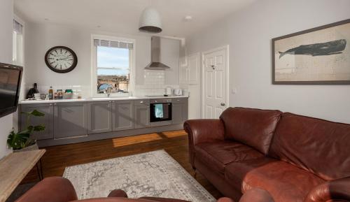 a living room with a couch and a clock on the wall at The Drawing Office in Berwick-Upon-Tweed