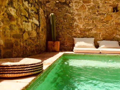 a swimming pool next to a stone wall with a cactus at Casa Migdia in Sant Jordi Desvalls