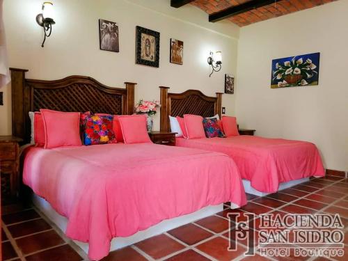 two beds with pink covers in a room at Hotel Hacienda San Isidro in San Isidro Mazatepec