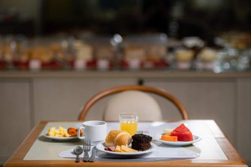 a table with two plates of fruit and a glass of orange juice at Rede Andrade Express in Salvador