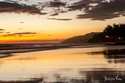 a sunset on a beach with the ocean at Olas Permanentes El Zonte in El Zonte