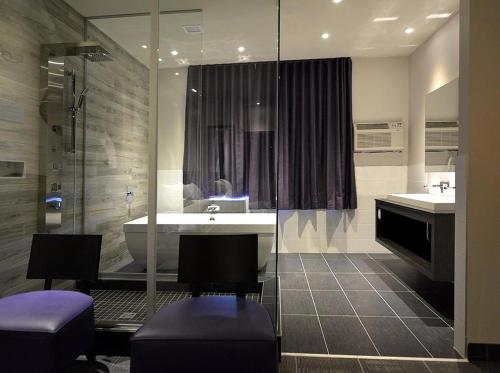 a bathroom with a tub and a sink and a shower at Hôtel Ô Laval in Laval