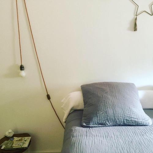 a bed with a blue pillow and a lamp on the wall at les Didascalies in Vic-Fezensac