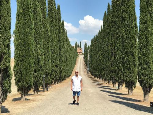 a man standing on a road lined with trees at BelSentiero in Campiglia dʼOrcia