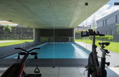a swimming pool with two exercise bikes next to it at Green Island Beach Villa, Apartment in Ponta Delgada