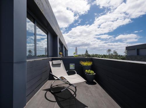 a balcony with a chair on a building at Green Island Beach Villa, Apartment in Ponta Delgada