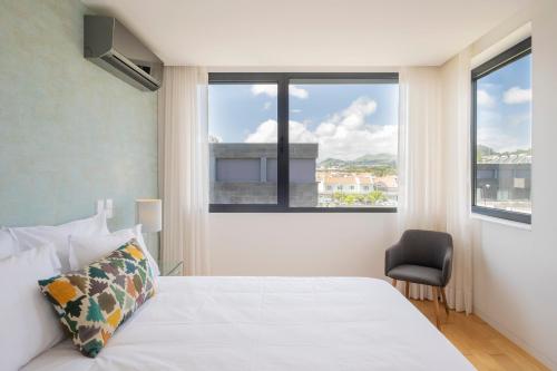 1 dormitorio con 1 cama, 1 silla y 2 ventanas en Green Island Beach Villa, Apartment, en Ponta Delgada