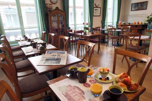 un restaurante con mesas y sillas con comida. en Hotel des Celestins, en Lyon