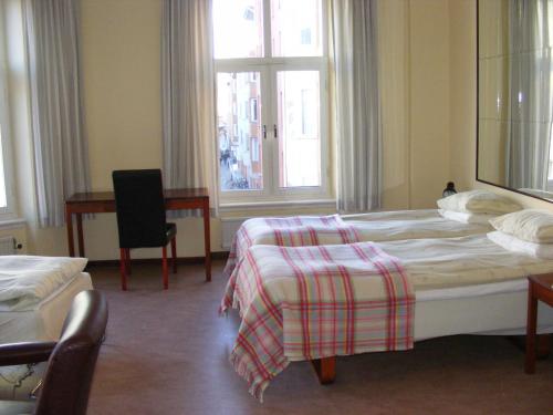 a bedroom with a bed and a desk and a window at Hotel Continental Malmö in Malmö