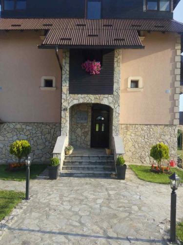 een gebouw met een deur, trappen en bloemen bij Apartments NS Novaković in Zlatibor