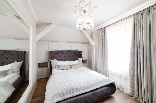 Habitación blanca con cama y lámpara de araña. en LUX apartment on Duhnovicha street .Free parking., en Uzhhorod