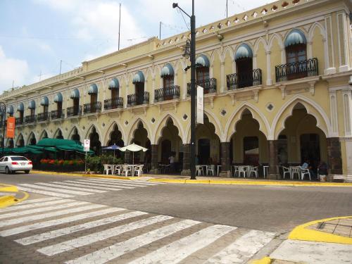 a building with tables and umbrellas on a city street at Hotel Concierge Plaza Colima in Colima