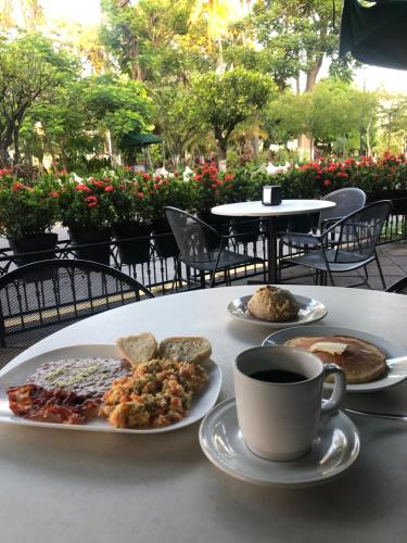 a table with two plates of food and a cup of coffee at Hotel Concierge Plaza Colima in Colima