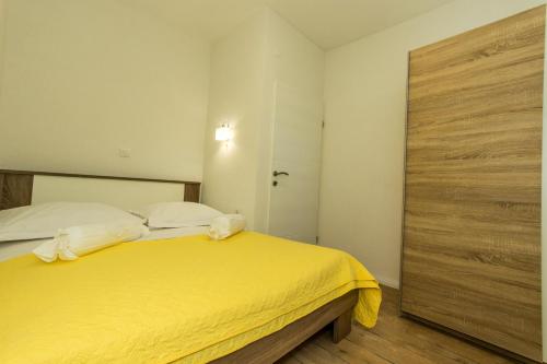 a bedroom with a yellow bed and a wooden door at Bluesun Sibenik Apartments in Šibenik