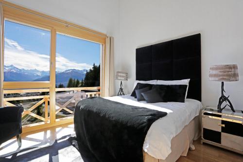 a bedroom with a bed and a large window at Crans Luxury Lodges in Crans-Montana