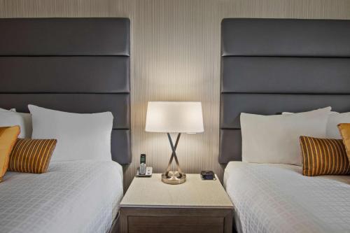 a bedroom with two beds with a lamp on a night stand at Best Western Premier Calgary Plaza Hotel & Conference Centre in Calgary