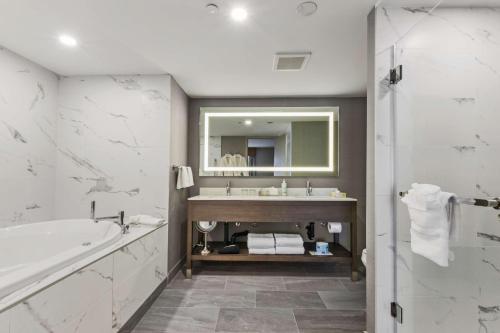 カルガリーにあるBest Western Premier Calgary Plaza Hotel & Conference Centreのバスルーム(バスタブ、シンク、鏡付)