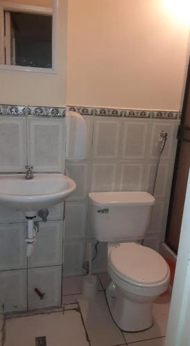 a white bathroom with a toilet and a sink at Hotel Fika Guayaquil in Guayaquil