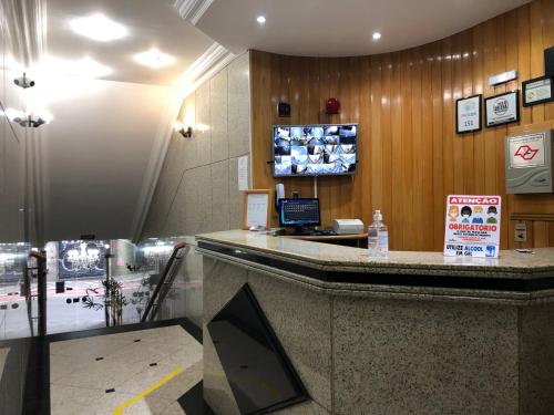 a hotel lobby with a counter with a tv on the wall at Paissandú Palace Hotel - Próximo às ruas 25 de Março, Sta Ifigênia e regiões do Brás e Bom Retiro in Sao Paulo