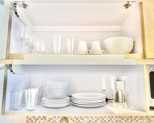 a cupboard filled with plates and glasses and dishes at Oceanview Beach Block BALCONY Ocean and City View in San Juan