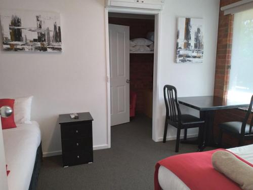 a hotel room with a desk and a bed and a desk at Pevensey Motor Lodge in Echuca