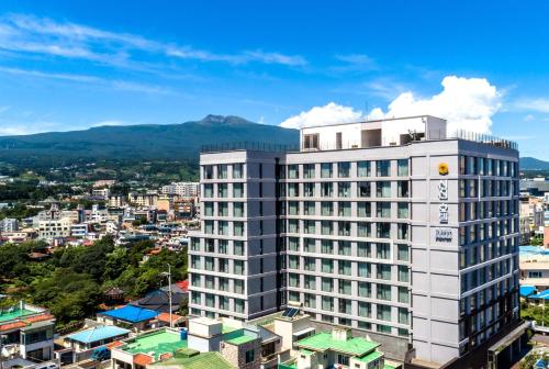 a tall white building in front of a city at Shin Shin Hotel Cheonjiyeon in Seogwipo