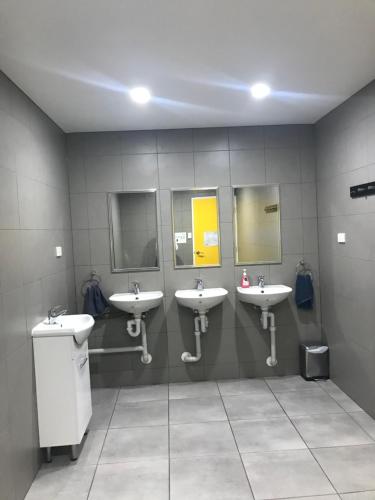 a bathroom with three sinks and three mirrors at Perth City Backpackers Hostel - note - Valid passport required to check in in Perth
