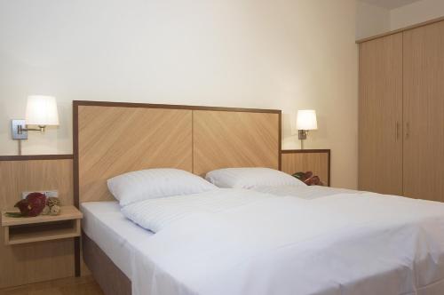una camera da letto con un grande letto bianco con due cuscini di Residenz am Dom Boardinghouse Apartments a Colonia