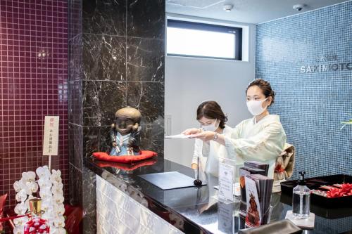 a woman wearing a face mask in a bathroom at Hotel S-Presso Central in Osaka